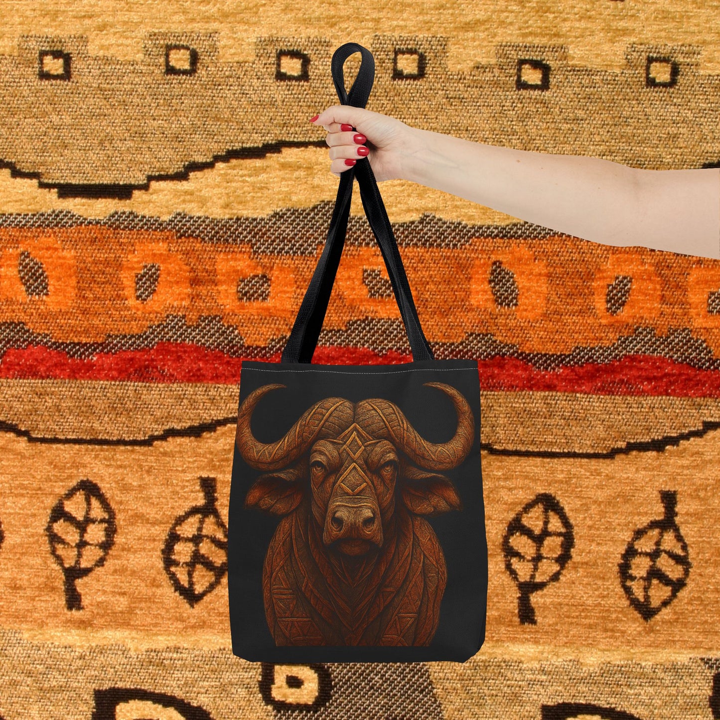 Mashafrica black tote bag with carved buffalo artwork and long straps held over woven rug background