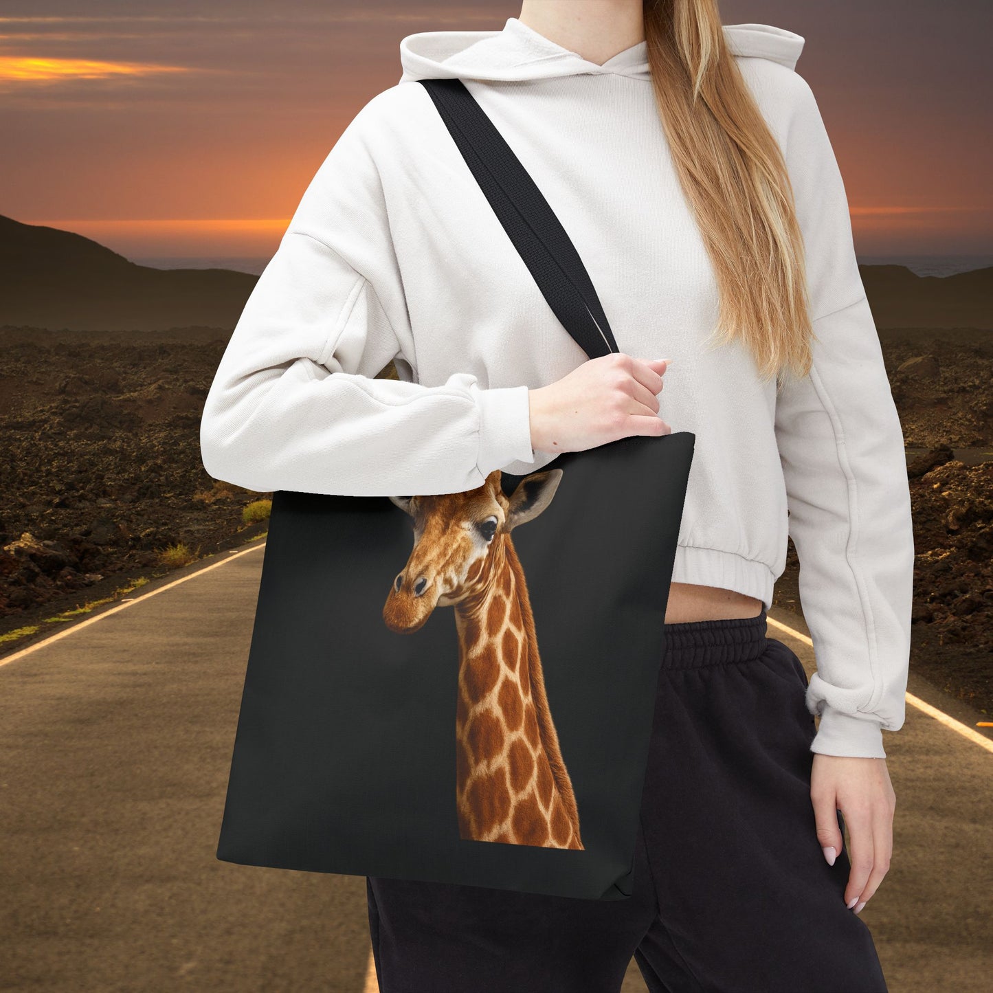 Mashafrica black canvas tote bag with realistic giraffe print shown on model wearing hoodie at sunset