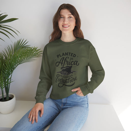 Woman wearing green Mashafrica sweatshirt with African-inspired design sitting by a green plant