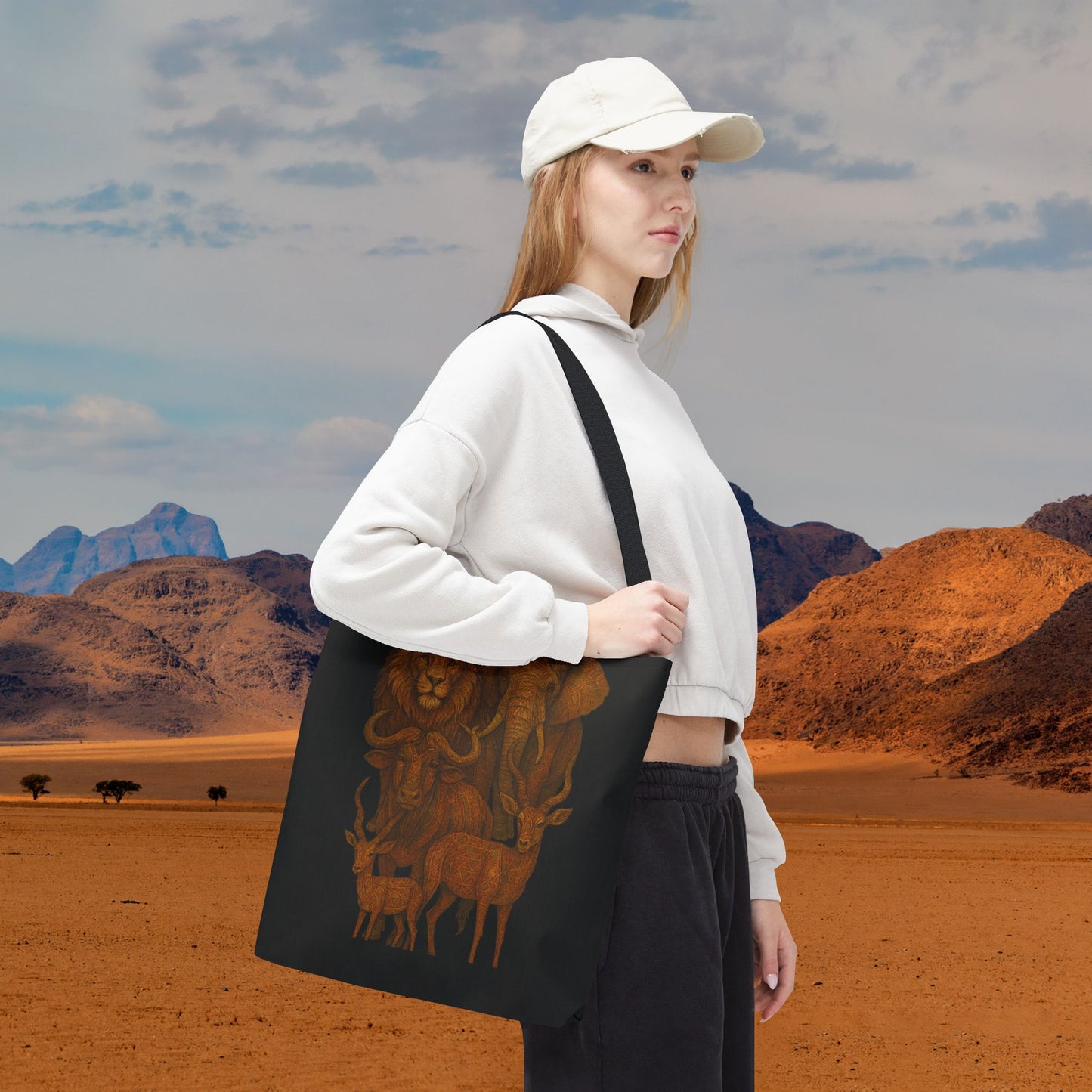 Mashafrica black canvas tote bag with brown African wildlife print carried by woman in white hoodie