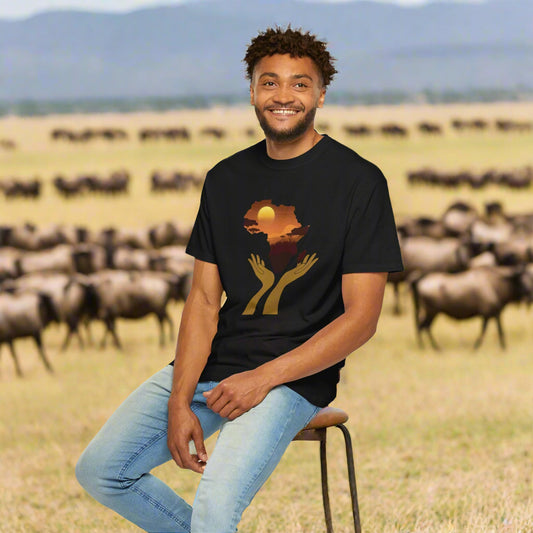 Smiling man wearing Mashafrica black T Shirt with africa sunset silhouette and hands graphic in savanna