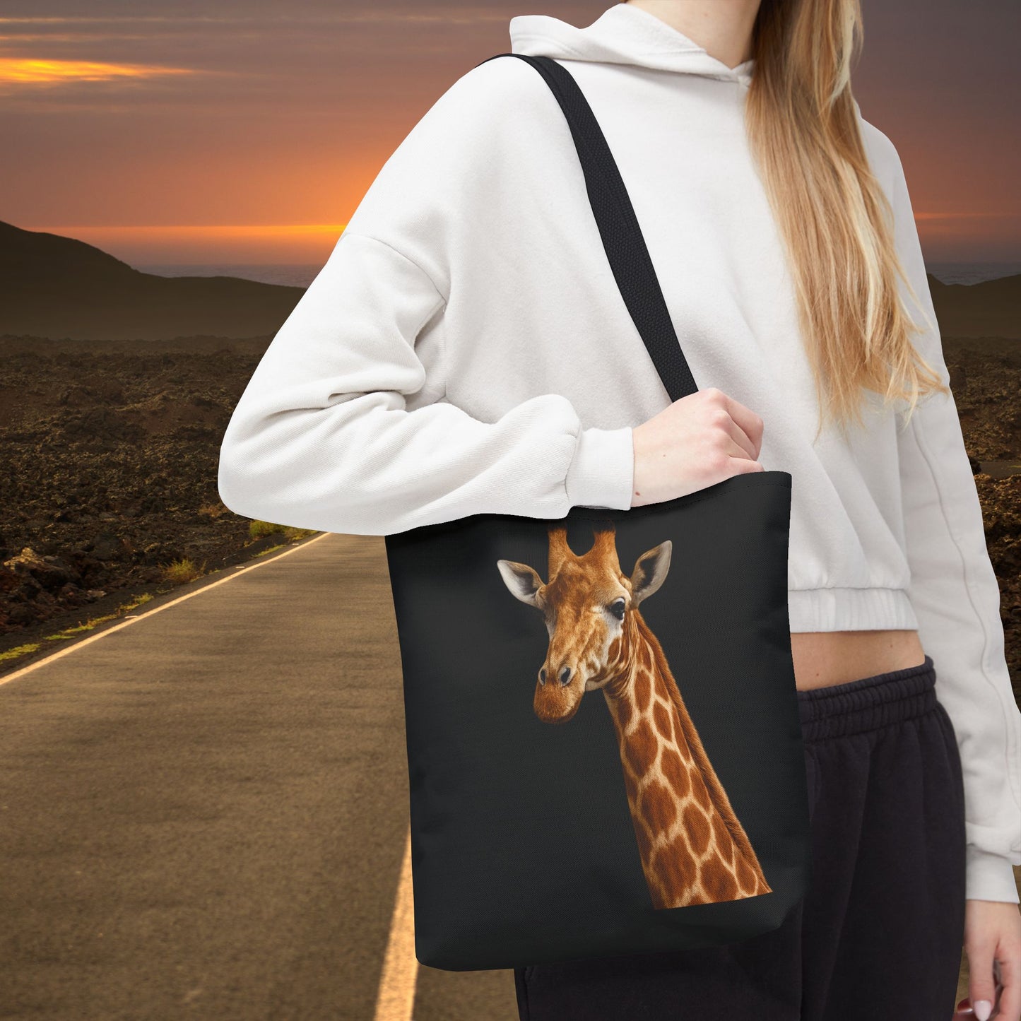Mashafrica black canvas tote bag with realistic giraffe print worn crossbody by model on road at sunset