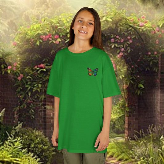 Young girl modeling Mashafrica kids green butterfly t shirt in garden backdrop smiling in oversized casual tee