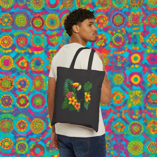 Mashafrica black tote bag with tropical toucan and hibiscus print carried by man against colorful patterned backdrop